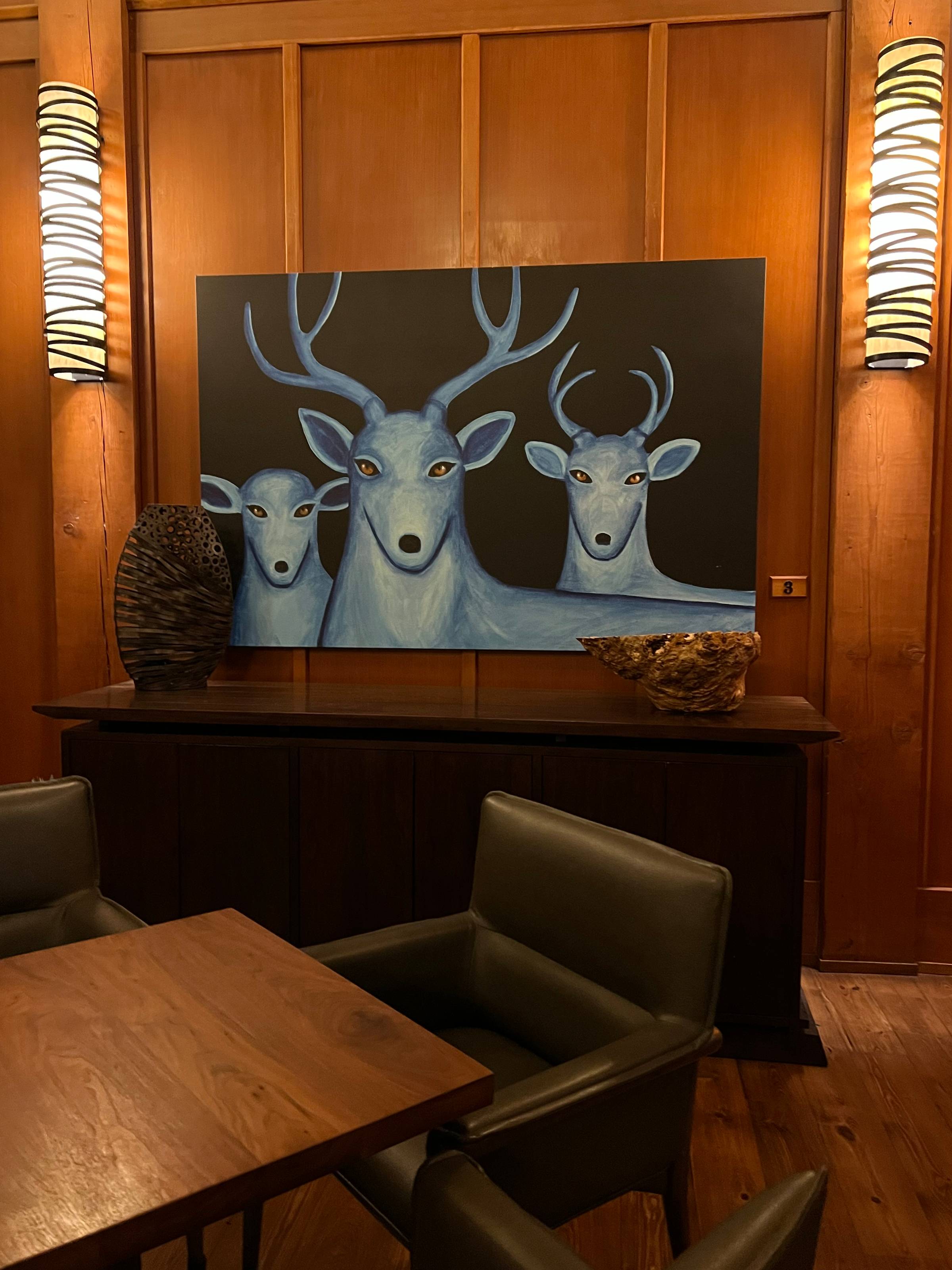 artwork of three blue deer on a wood panneld wall