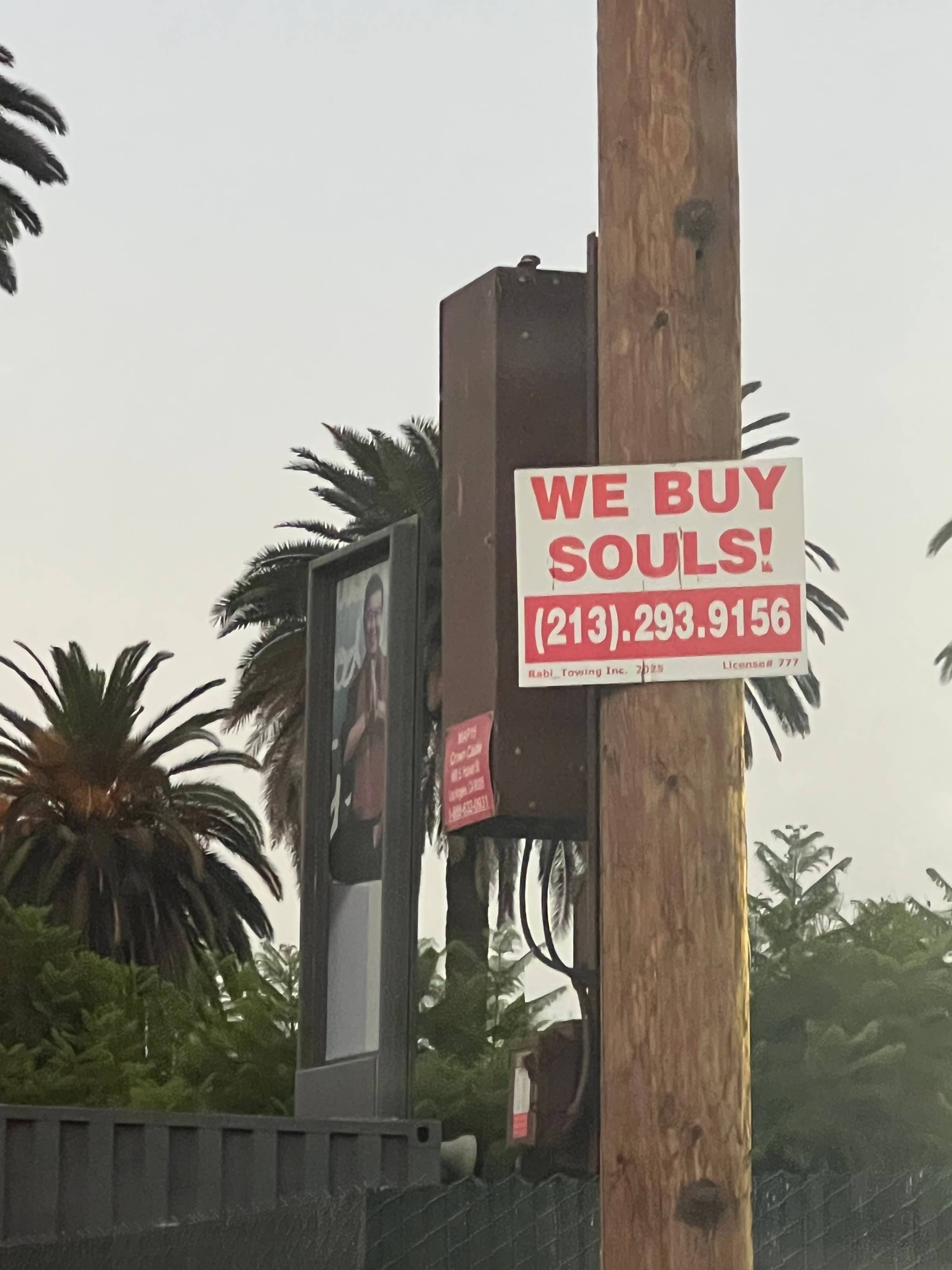 sign on telephone pole reading "WE BUY SOULS!"