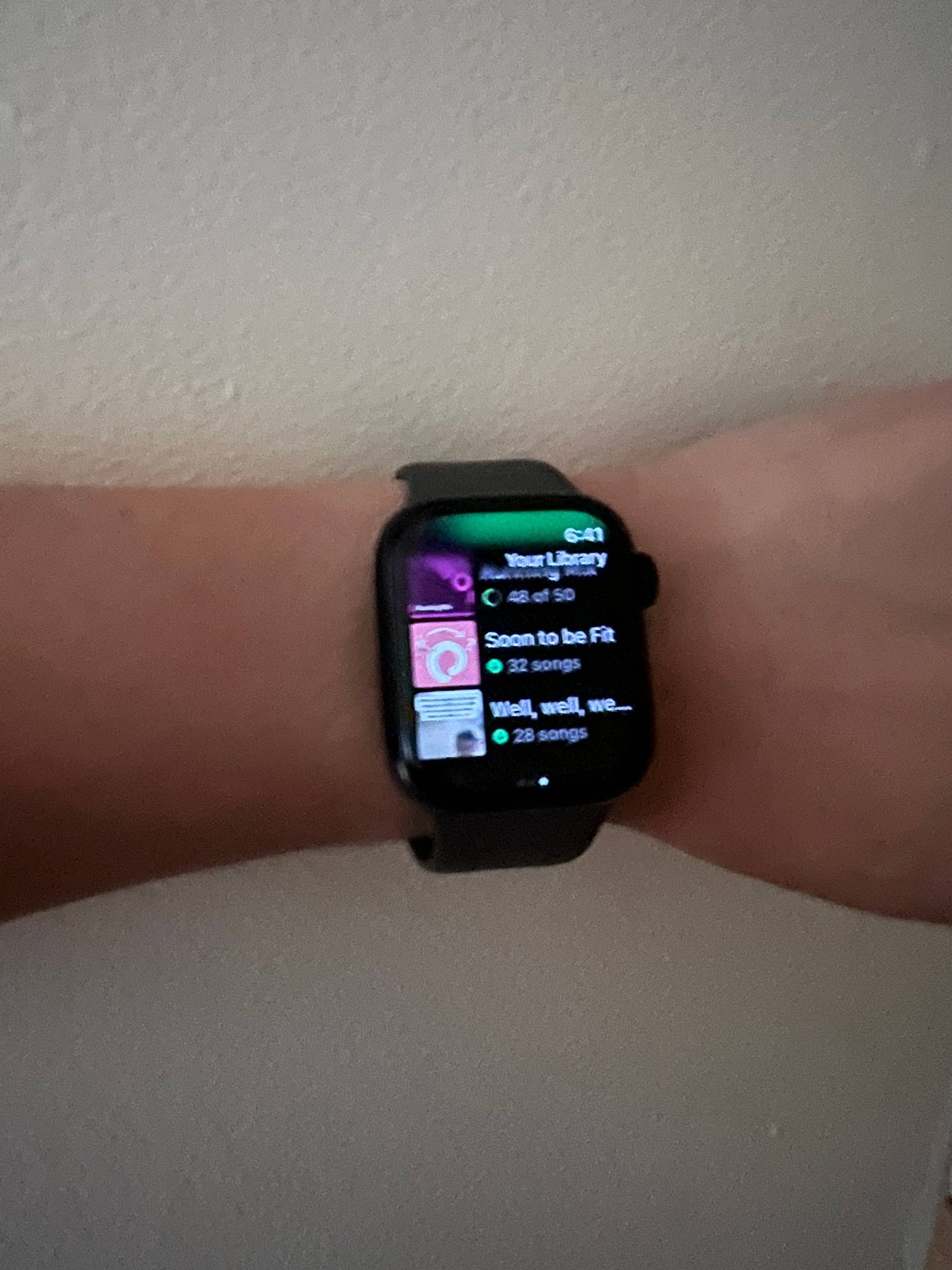 apple watch worn on wrist displaying playlist being downloaded