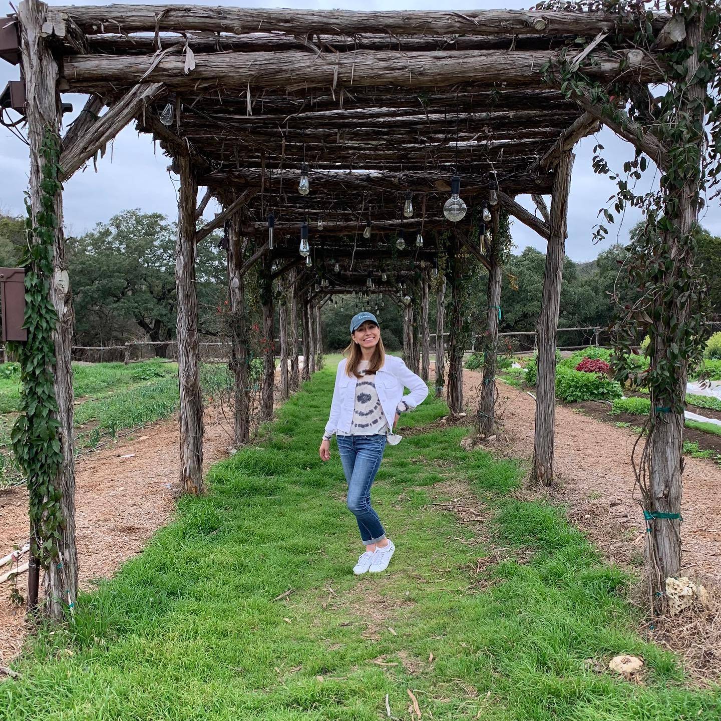 A woman,Chef Cindy, standing under a trellis on a farm 