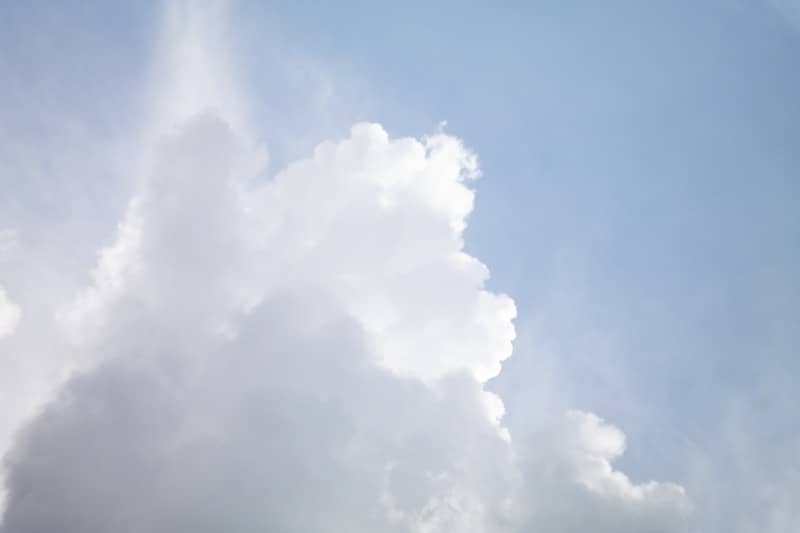 Fluffy white and grey clouds against a light blue sky.
