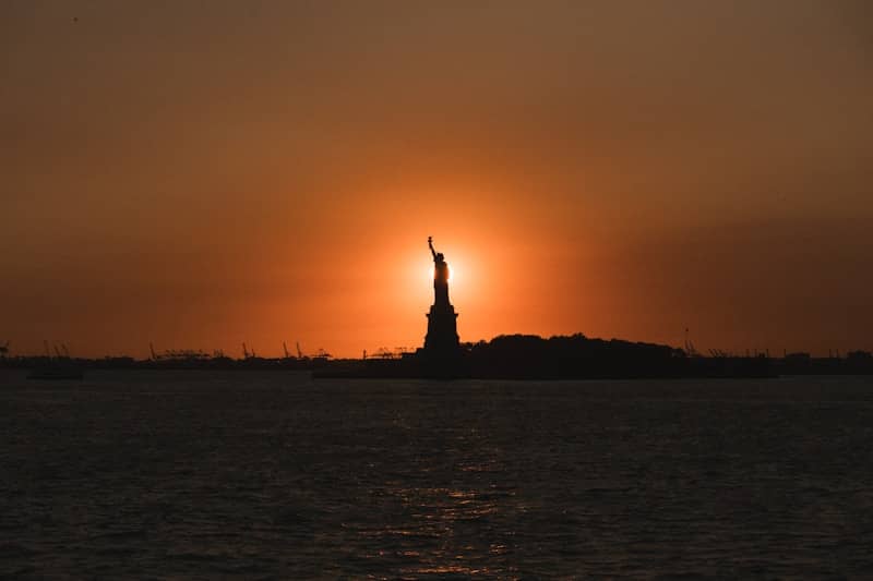 New york statue of liberty silhouetted at sunset