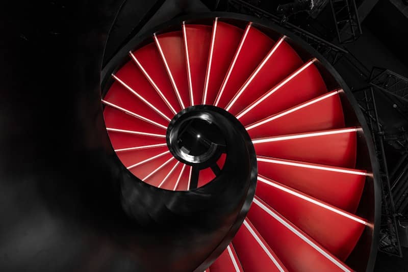 A glowing red spiral staircase descends into darkness.