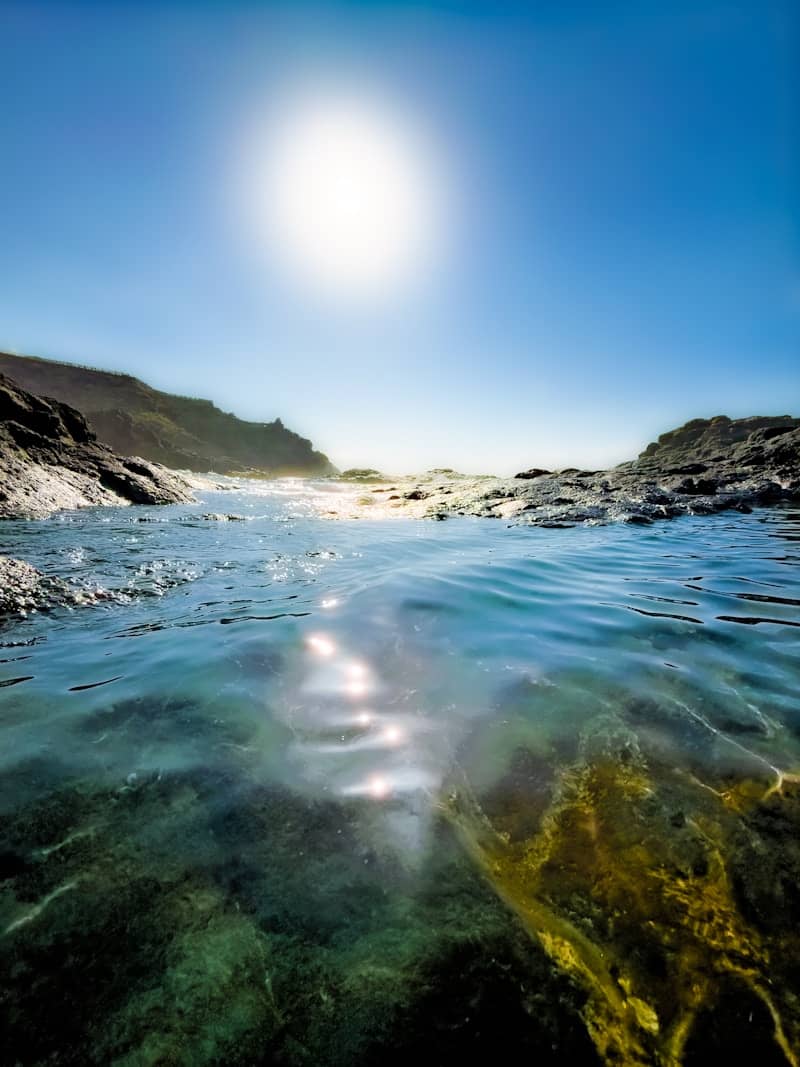 Clear water in a rocky tide pool under a bright sun in a blue sky