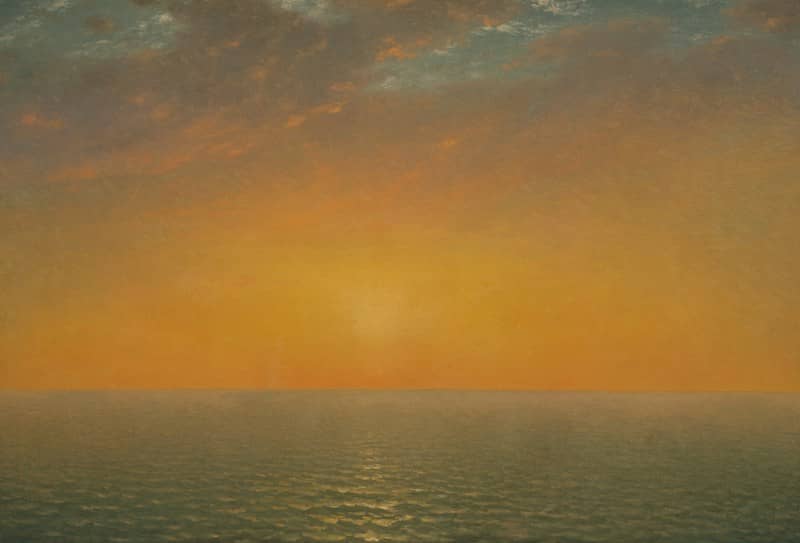 Low sun over a calm ocean under a warm orange sky