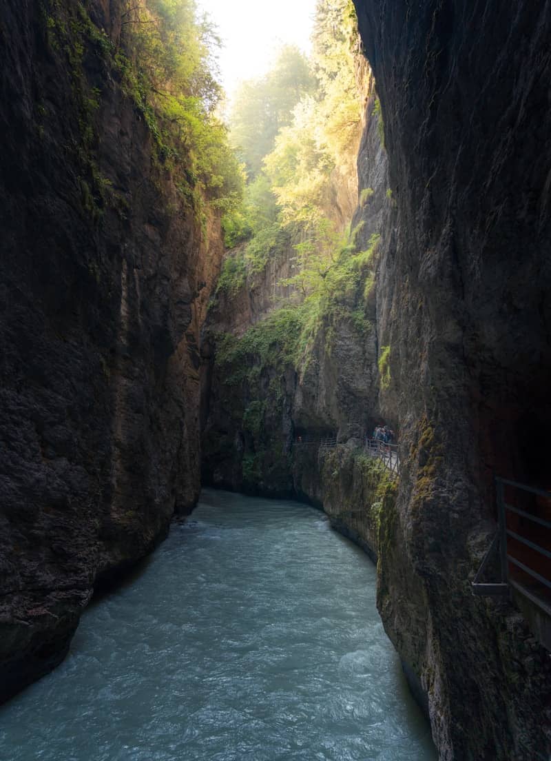 A river flowing through a deep rocky gorge with a narrow pedestrian walkway