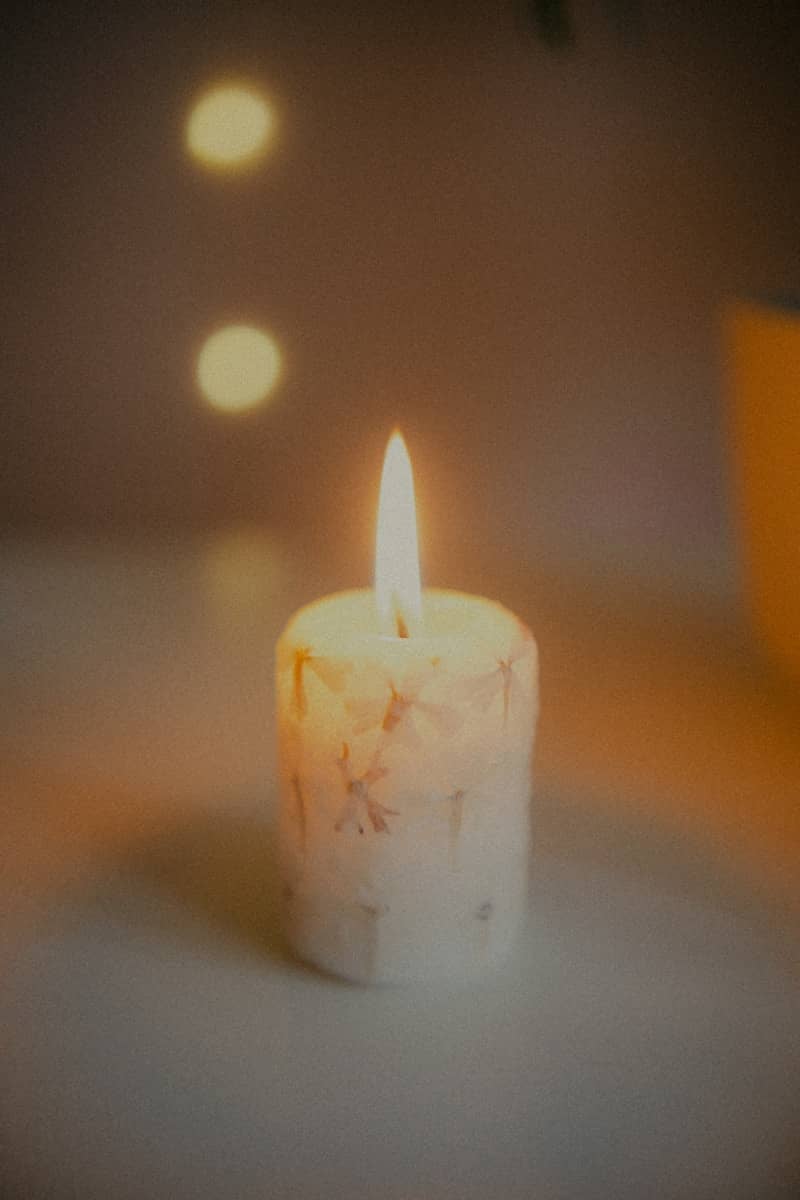 A lit candle with a flame on a blurred background.