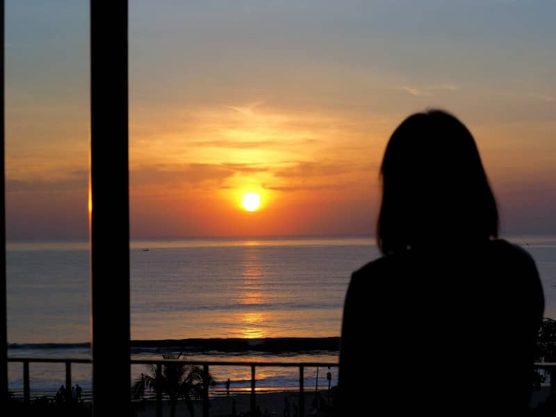 A person in silhouette looking out at the ocean during the golden hour