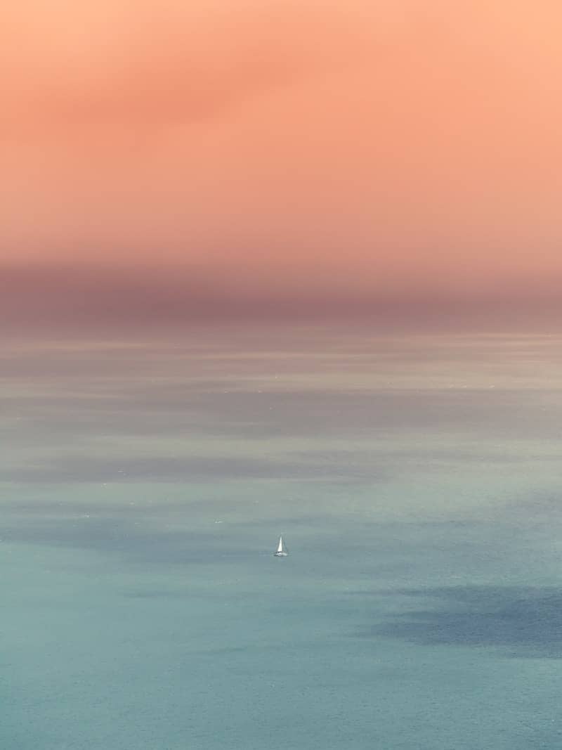 Sailboat on calm ocean at sunset