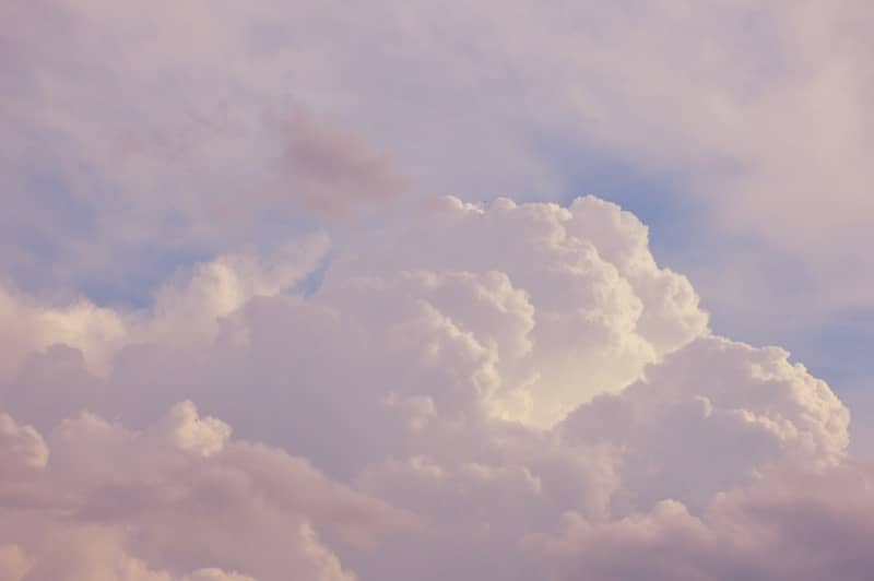 a plane flying through a cloudy blue sky