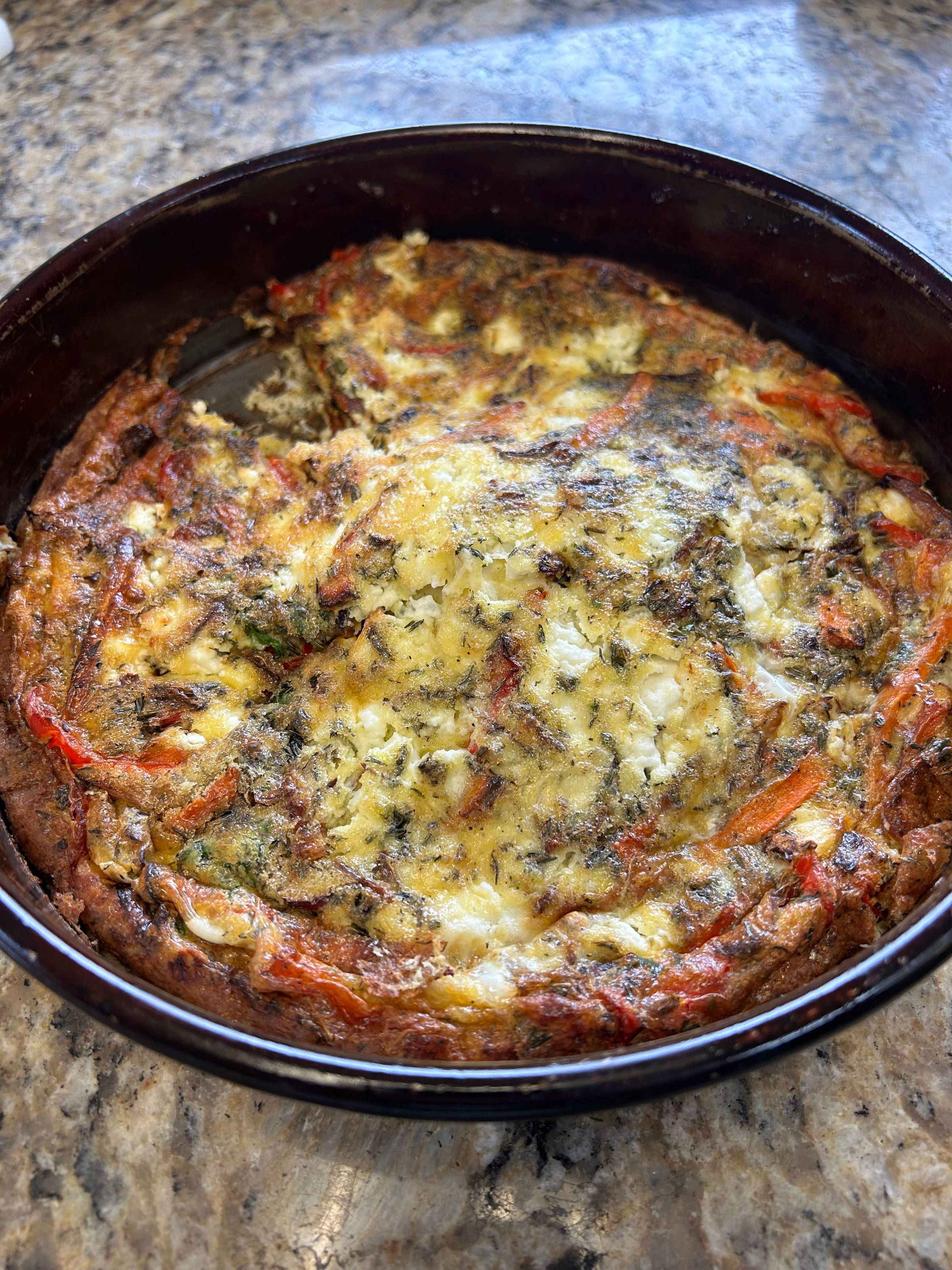 Herbed goat cheese egg bake topped with fresh parsley, baked until golden over roasted peppers, and onions.