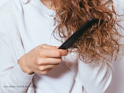 Curly-haired person combing through their hair.