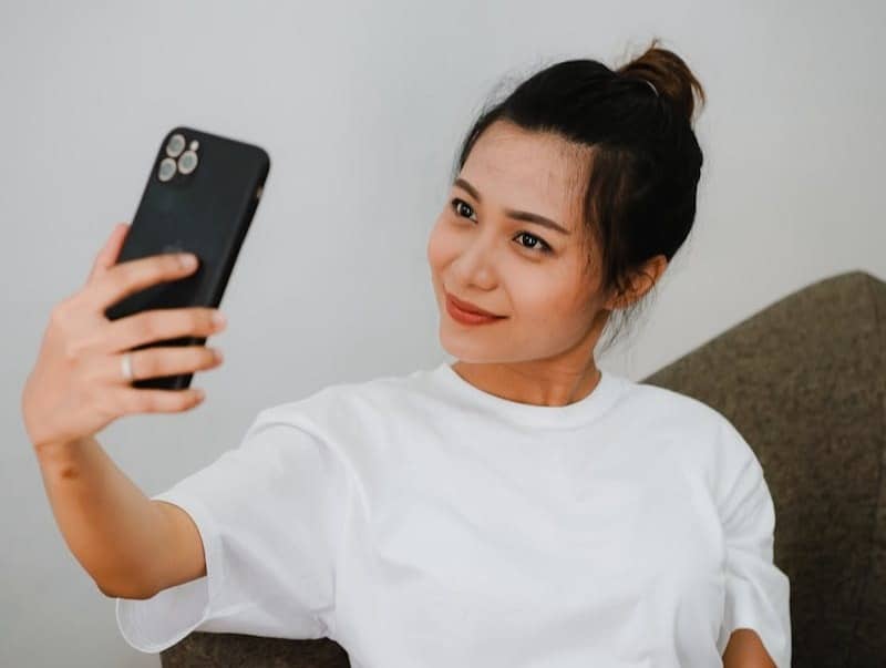 woman in white crew neck t-shirt holding black iphone 7 plus