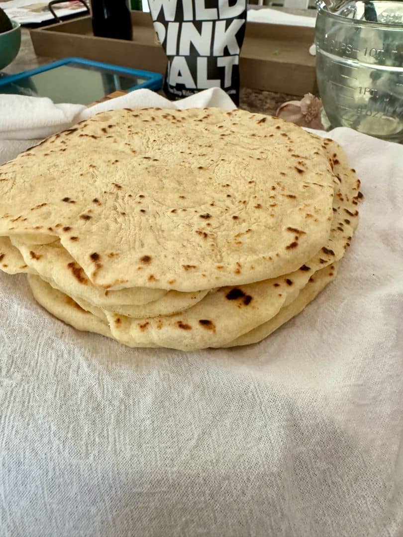 A stack of warm homemade flour tortillas with soft, tender layers and lightly toasted spots. Perfect for tacos, burritos, or wrapping up your favorite fillings.