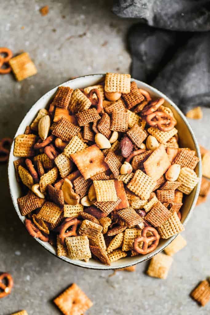 Chex cereal, cheese crackers, pretzels, nuts, and a simple homemade sauce make up this delicious Chex Mix! Served in a white bowl