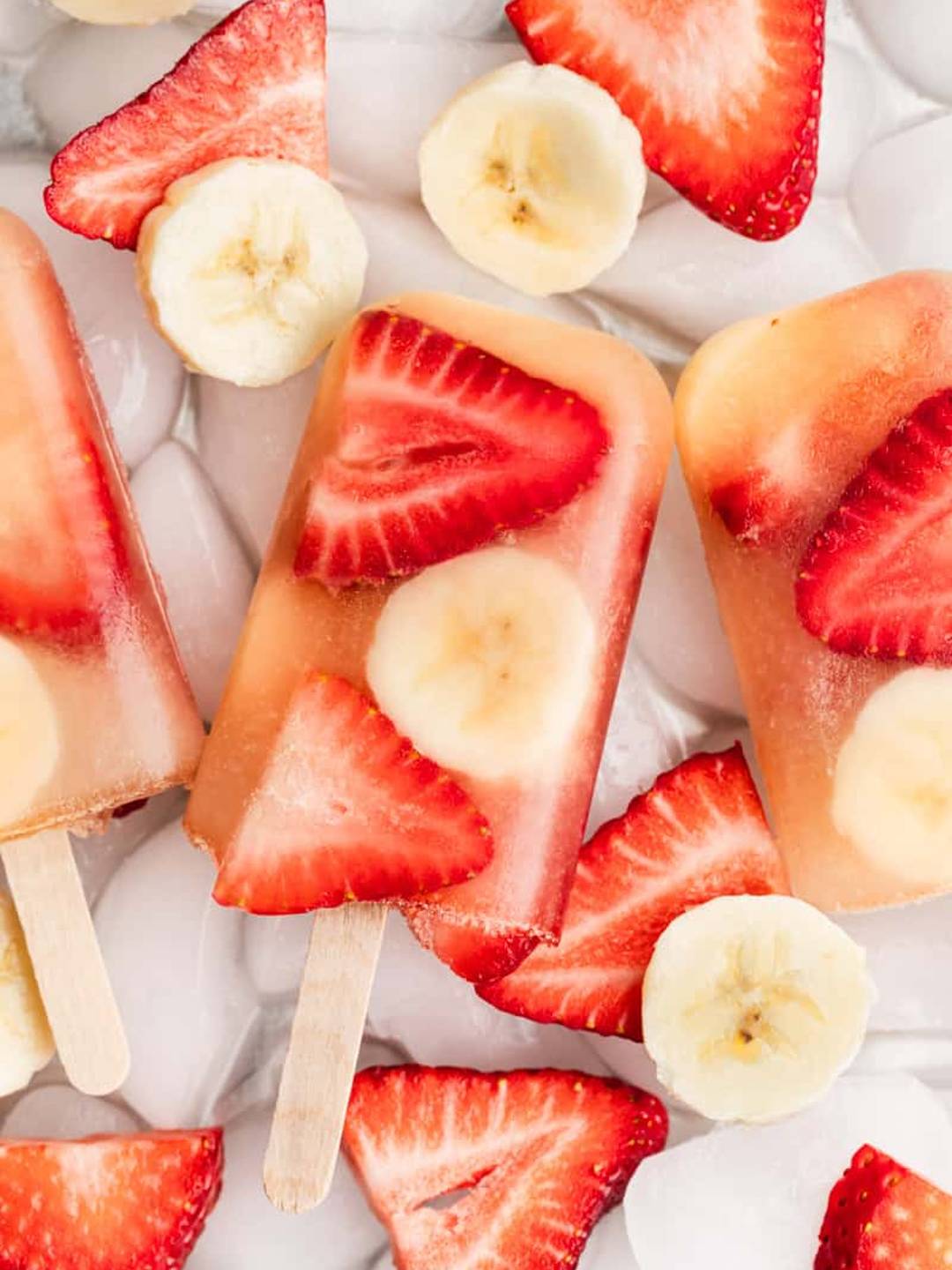 Fruit pops stacked together on a bed of ice.