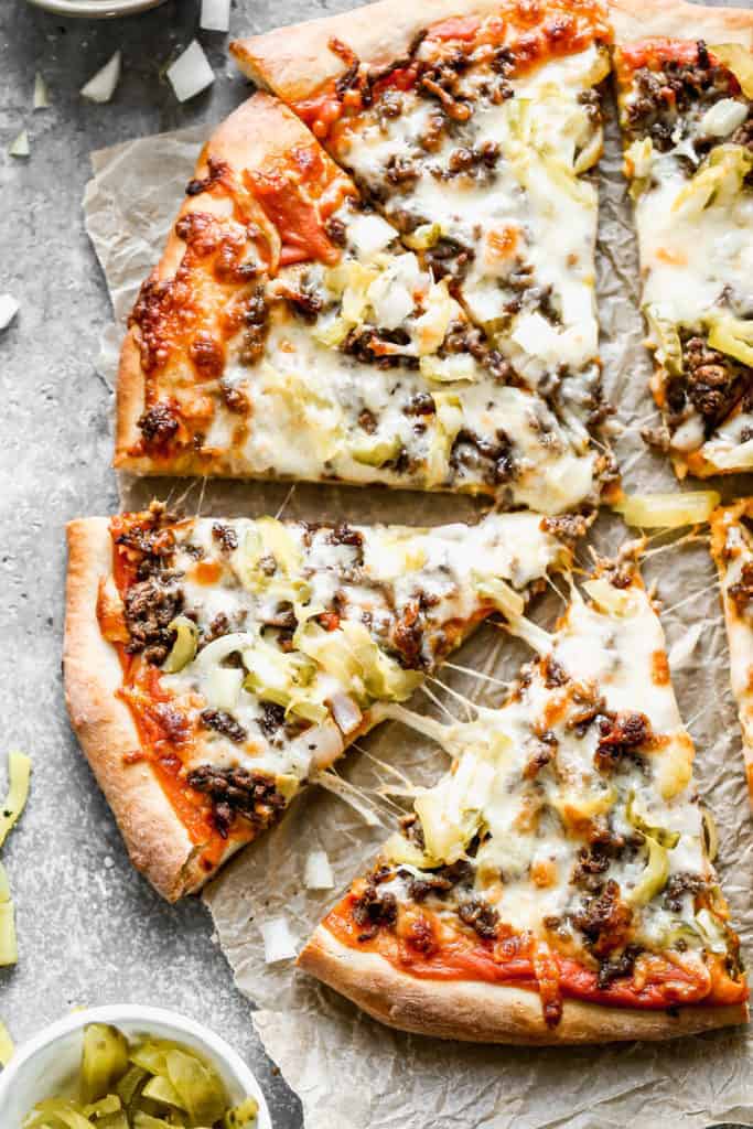 Cheeseburger pizza sliced and oozing with cheese and cheeseburger toppings