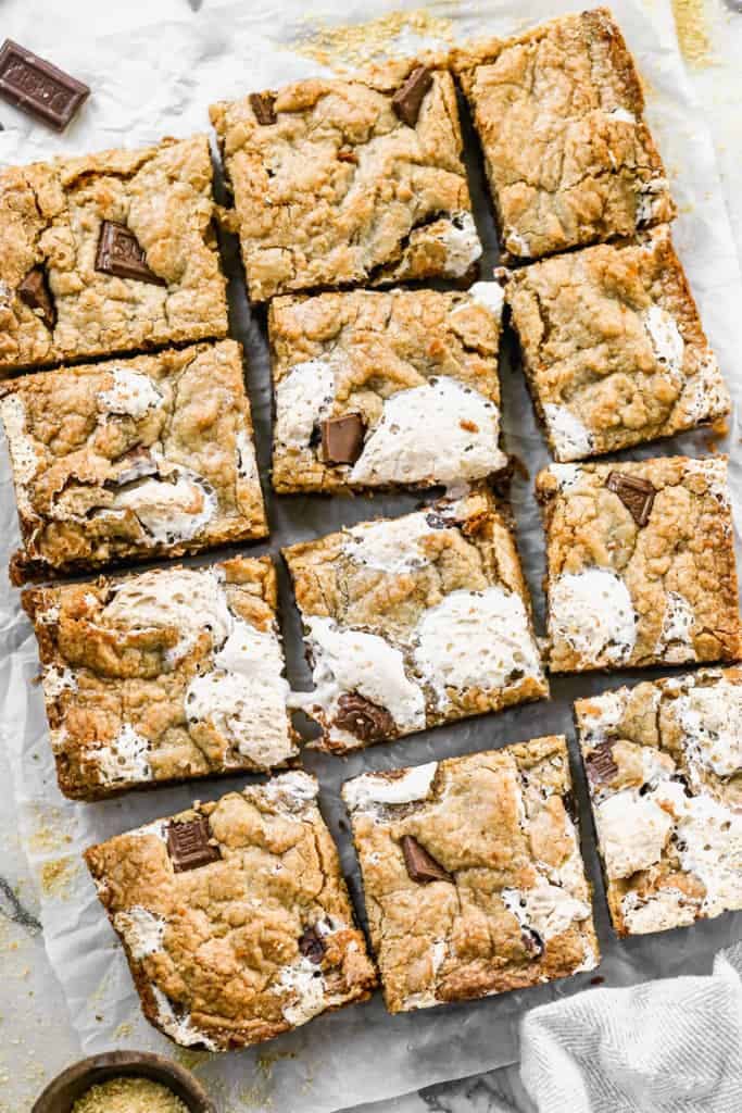 Smores Bars are a thick and chewy graham flavored cookie layered with marshmallow crème and chocolate. Cut into squares on a marble slab