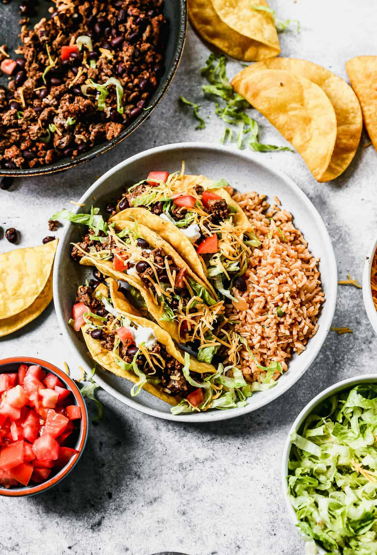 Ground beef tacos with all of the fixings like tomatoes, lettuce, guac