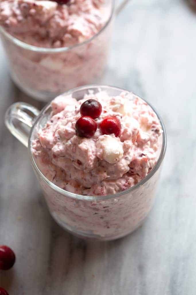 Fluffy Cranberry Salad served in a clear glass mug and topped with 3 cranberries.