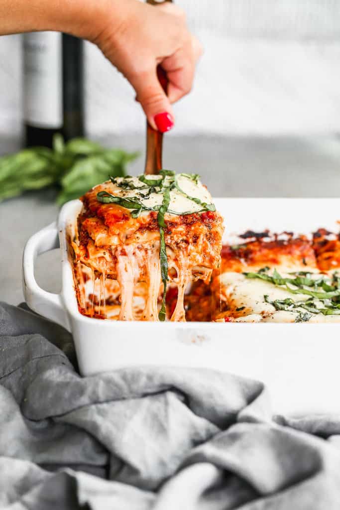 Homemade Lasagna in a white 9x13 pan being scooped out 