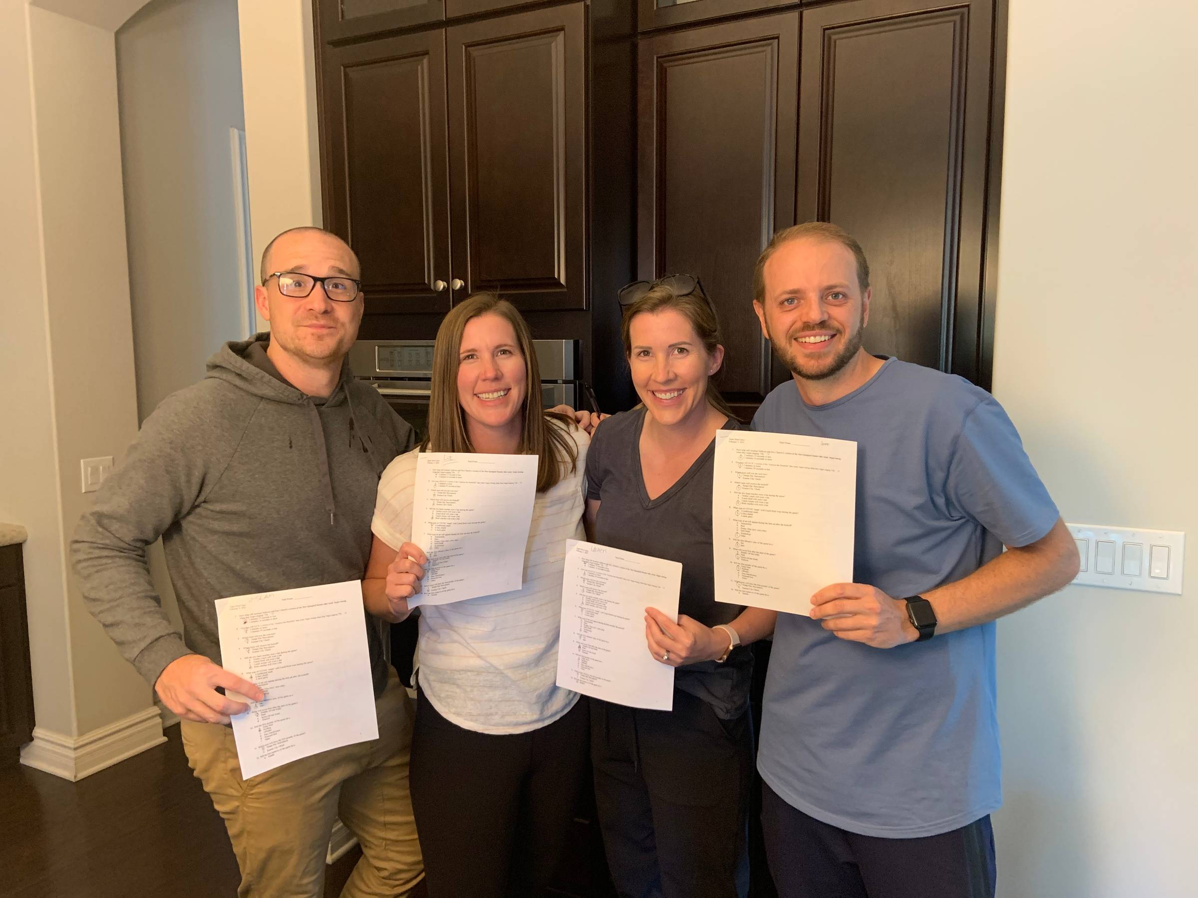 Liz and Lauren with their husbands and their Super Bowl Trivia Packets 