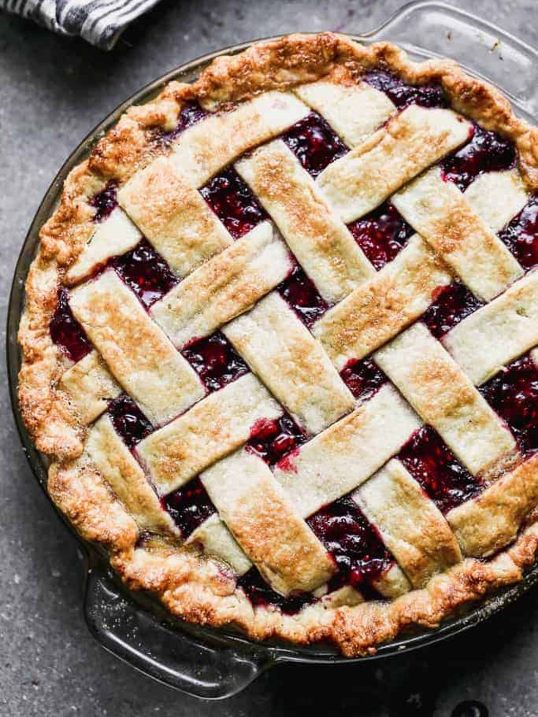 Triple Berry Pie with a lattace top served in a glass pie dish.