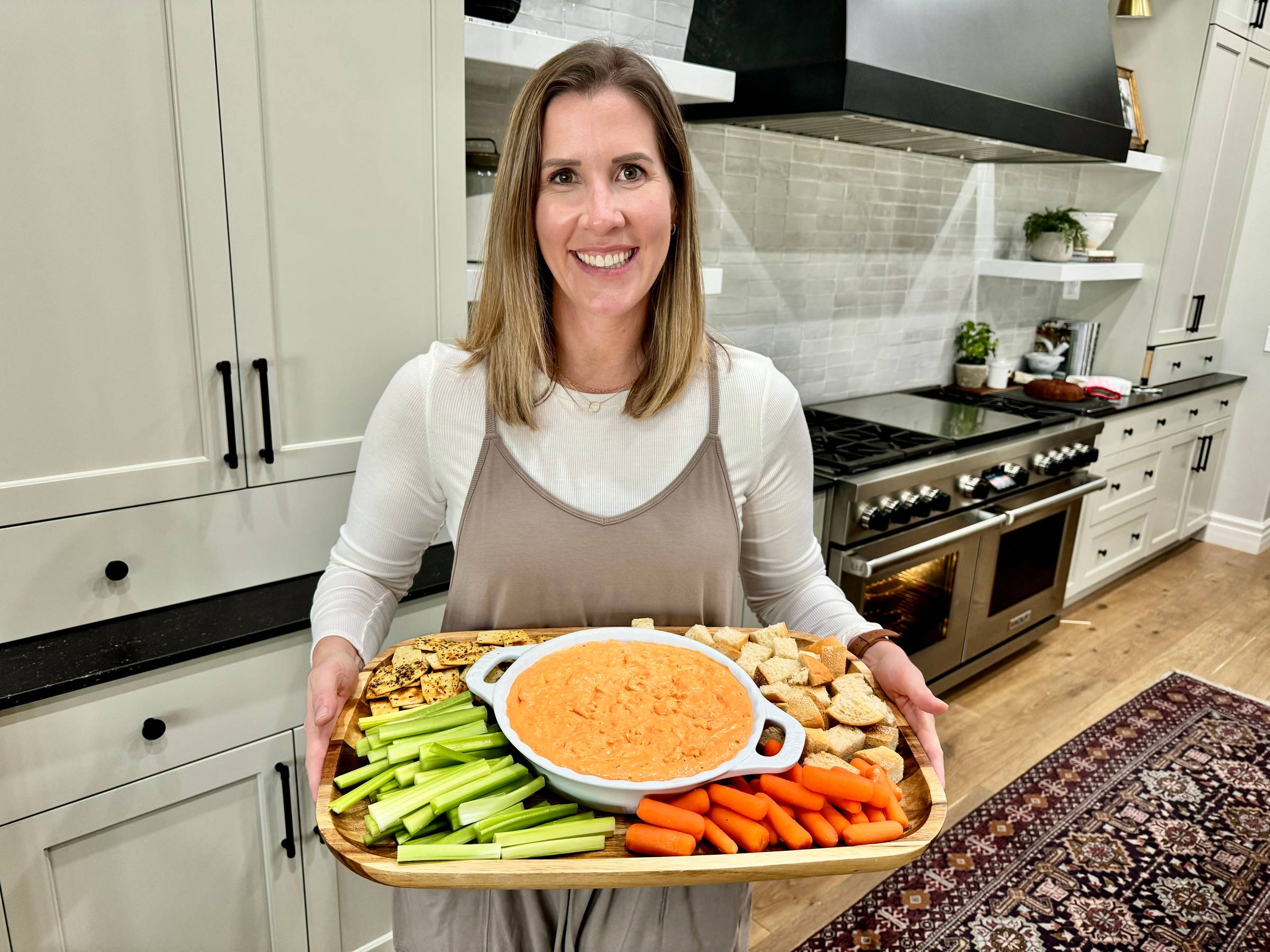 Lauren holding a tray of bread and veggies and a white dish of buffalo chicken dip