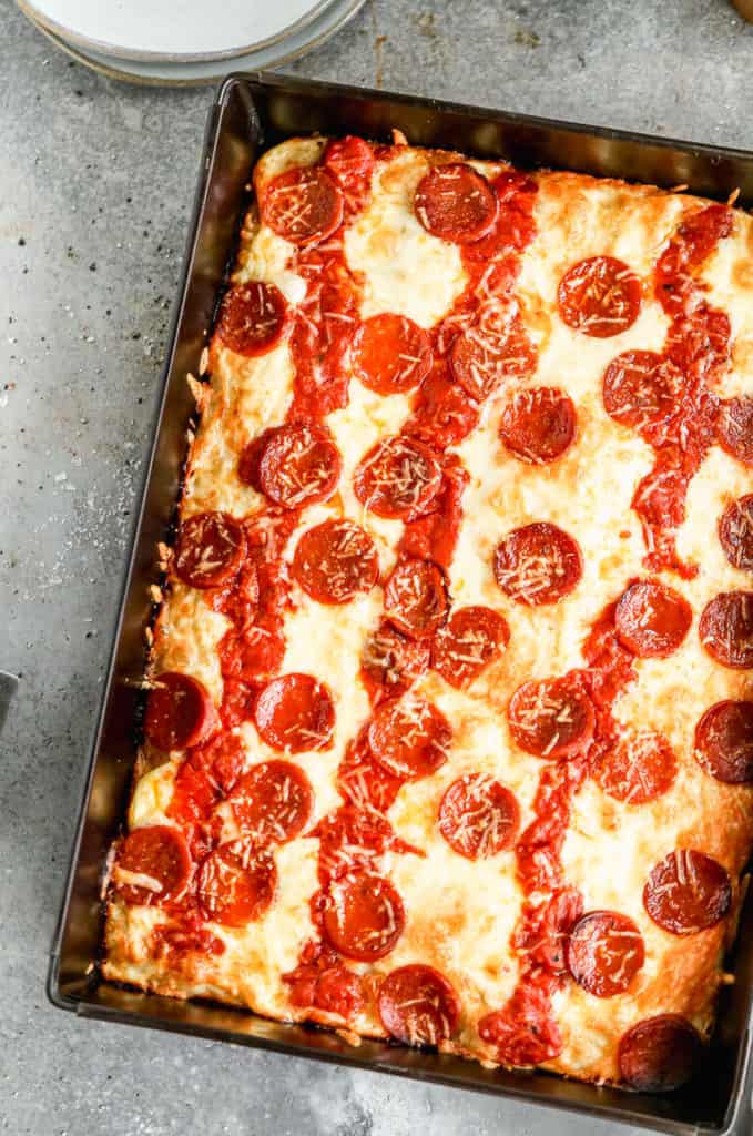 Detroit-style pizza in a metal rectangle pan topped with pepperoni and cheese