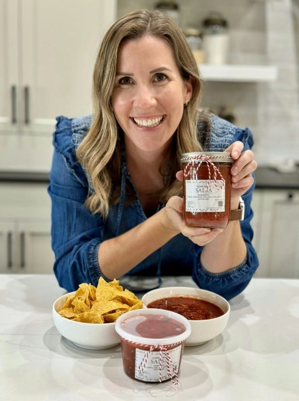 Lauren with homemade salsa in a jar with label. 