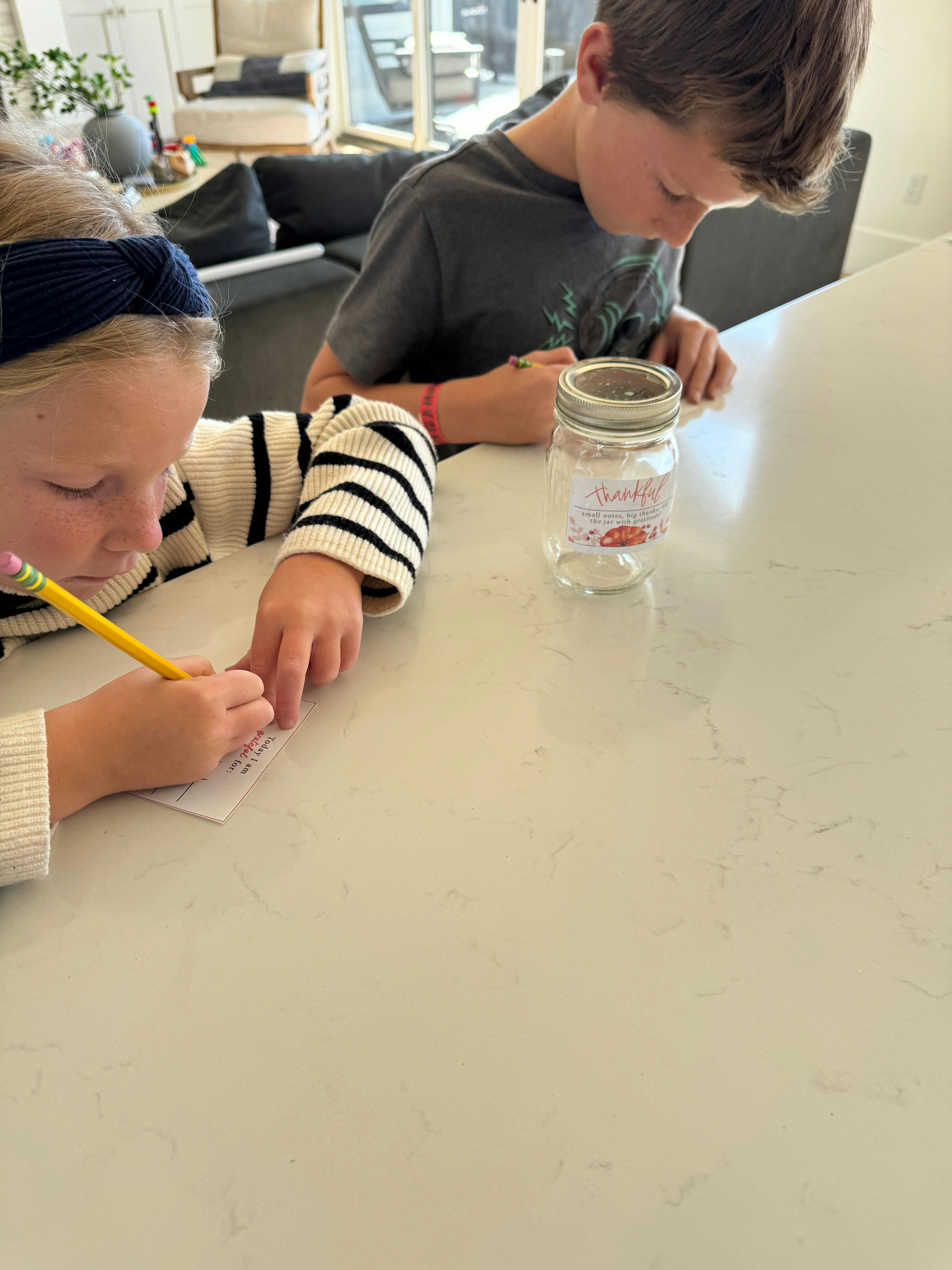 Liz's kids writing their gratitude lists for the jar.