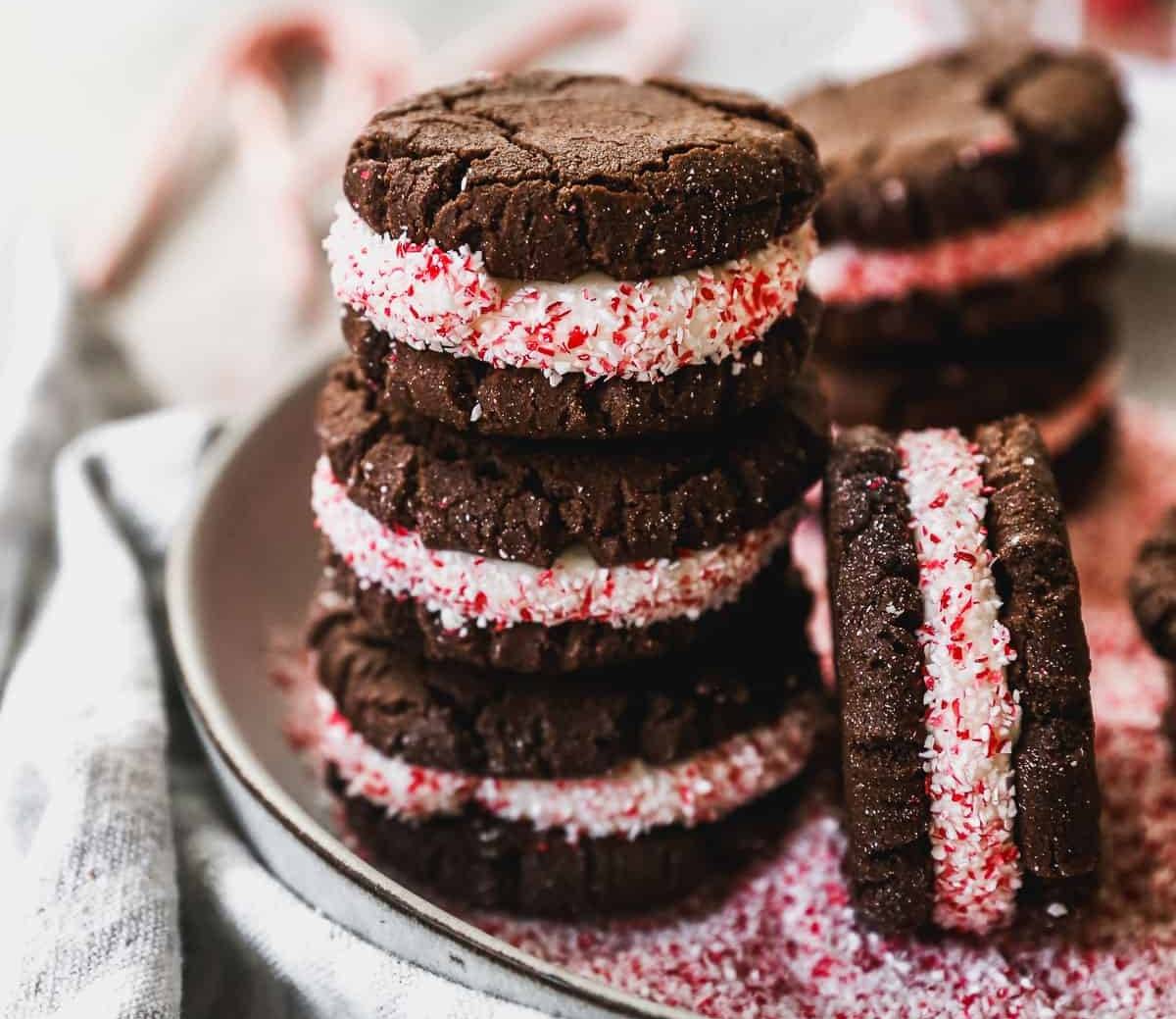A stack of easy Peppermint Oreos with crushed candy canes around the edges of the frosting, ready to eat. 