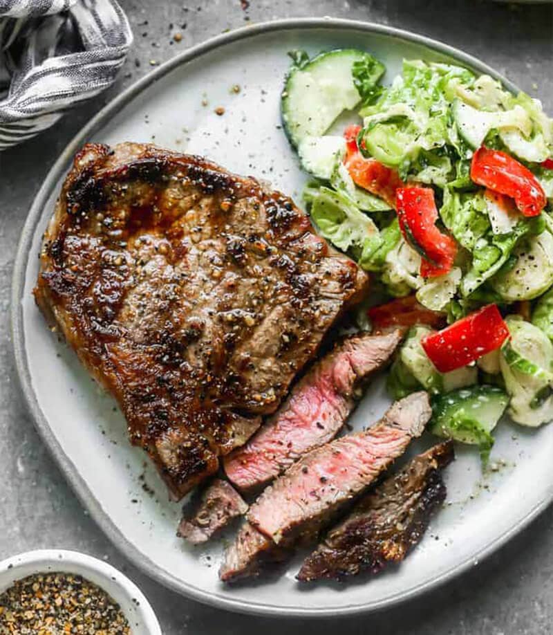Grilled Steak served with a side salad on a grey plate.