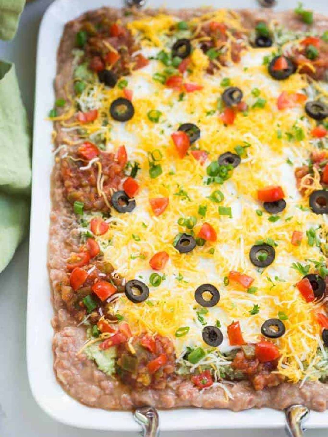 7 layer bean dip served in a white 9x13 baking dish.