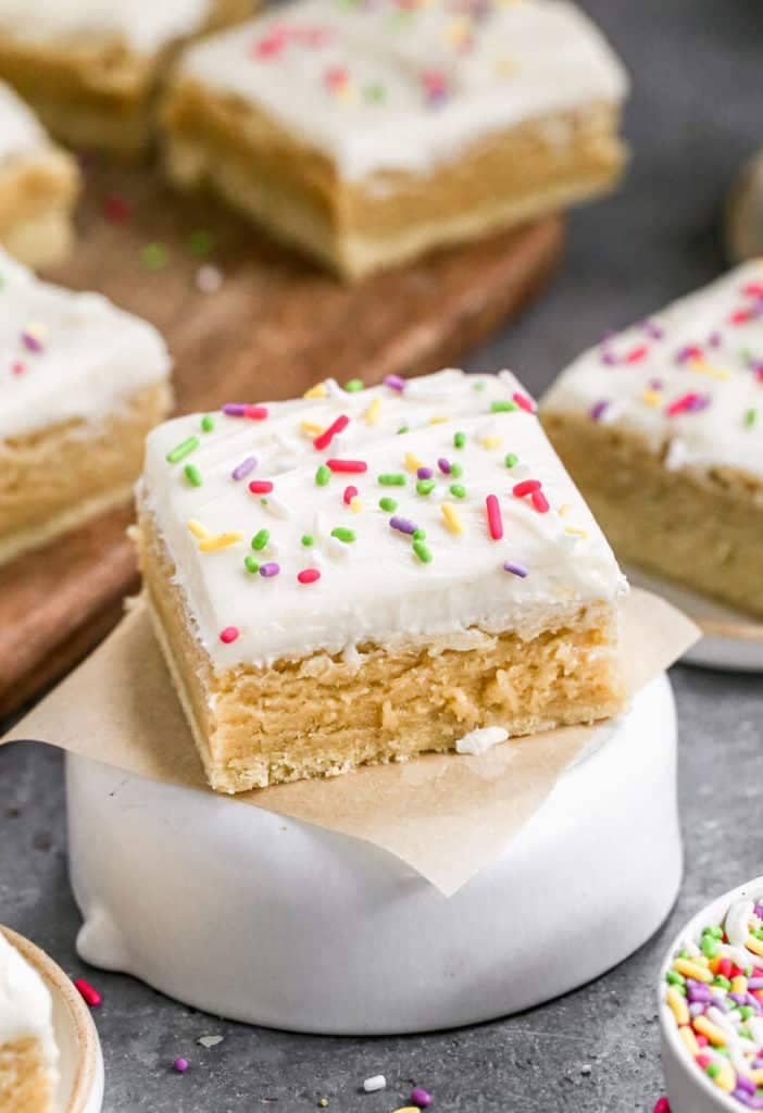 Sugar cookie bars covered in cream cheese frosting with colorful sprinkles