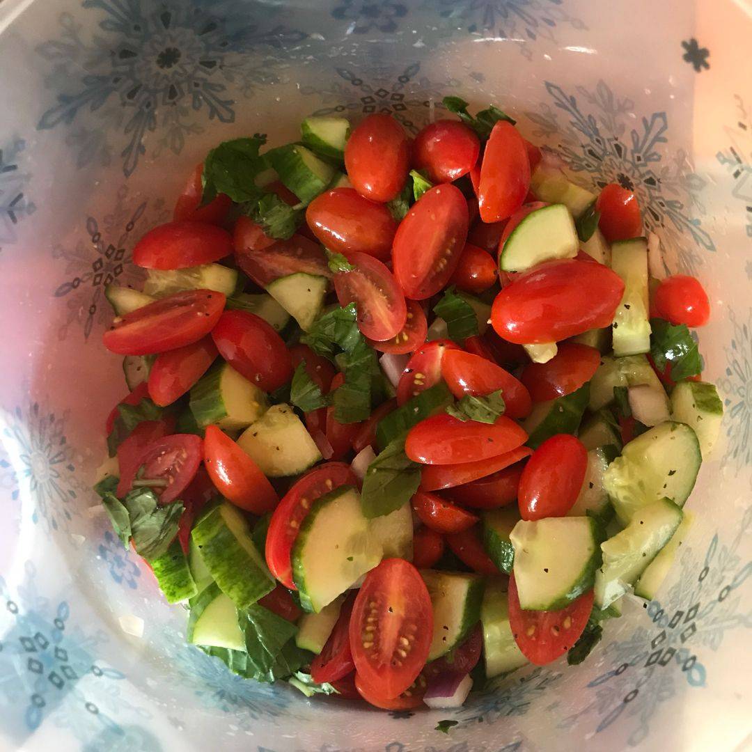 A vibrant bowl of fresh tomato cucumber salad with juicy cherry tomatoes, crisp cucumbers, red onion, and fresh herbs, all tossed in a light vinaigrettesummer in every bite.