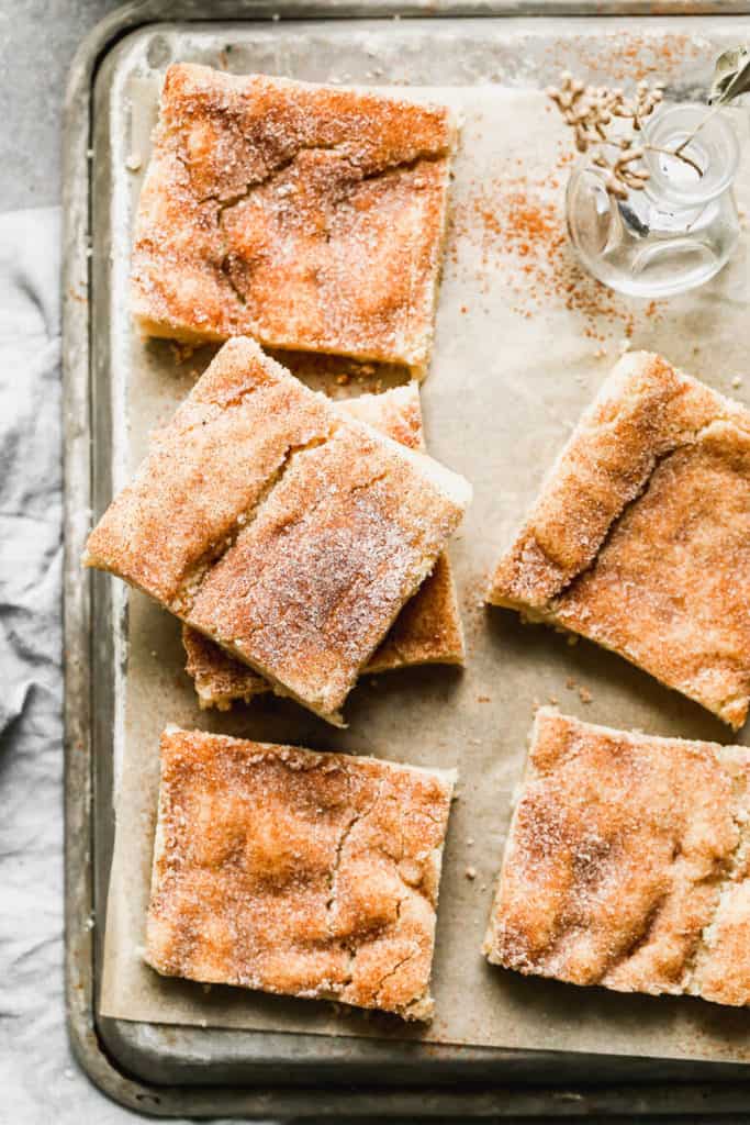 snickerdoodle bars stacked on a metal bakins sheet and parchment paper