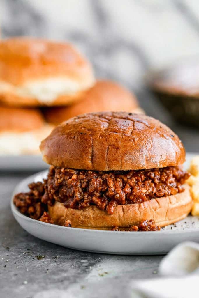 Sloppy Joes on a bun on a white plate with a side of fries