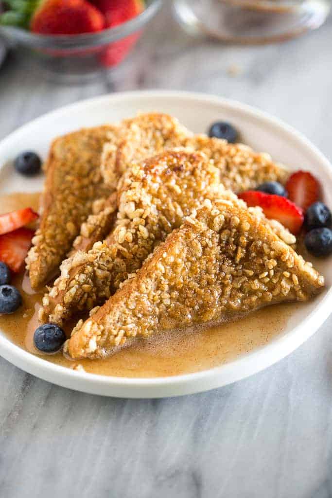 Crunchy French Toast topped with syrup, mixed berries and served on a simple white plate