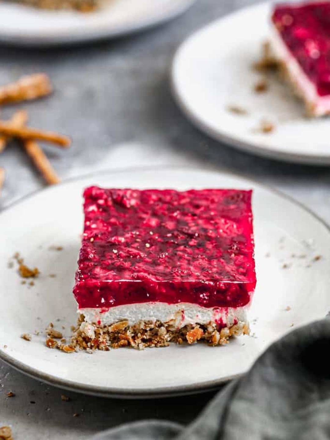 Pretzel Salad served on a white plate with blurred ingredients and another serving in the background.