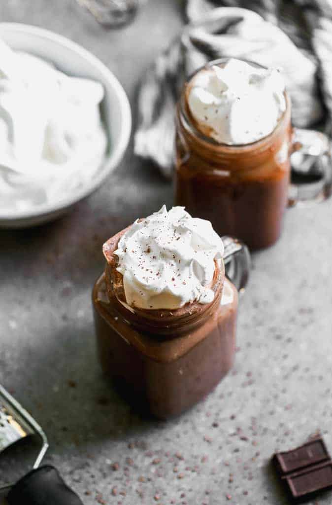 Creamy Hot Cocoa topped with homemade whipped cream and served in a clear mug