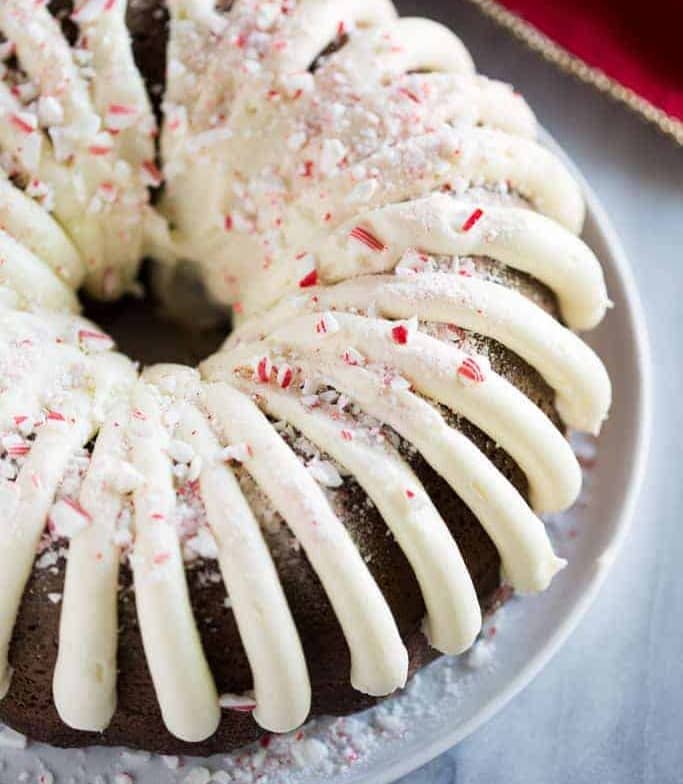 Chocolate Peppermint Bundt Cake on a white plate with crushed candy canes on top.