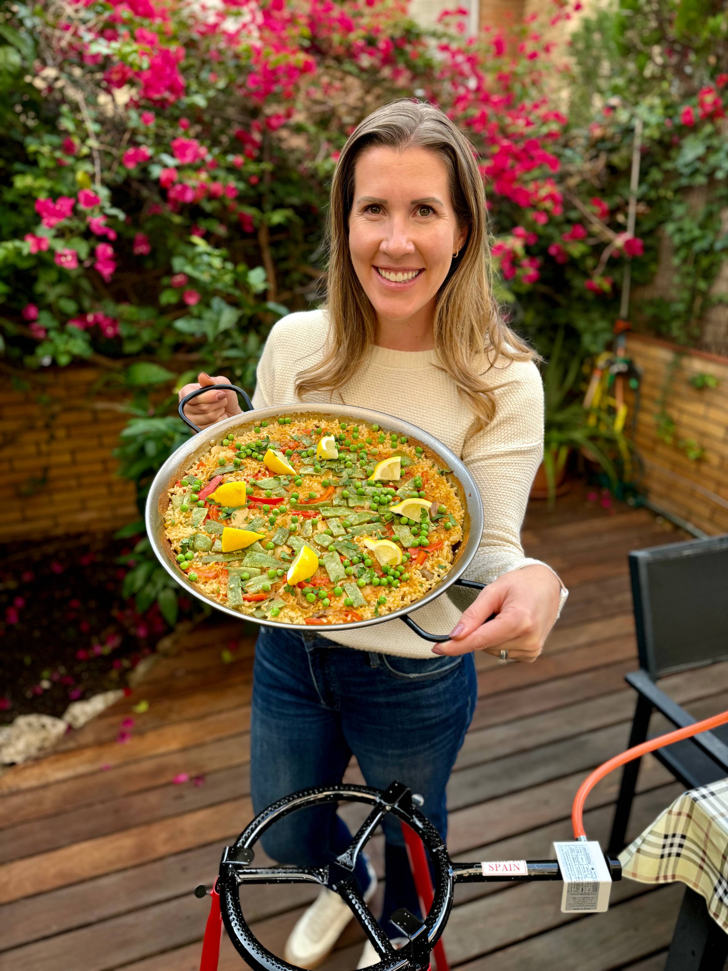 Lauren holding a paella pan full of vegetable Paella.