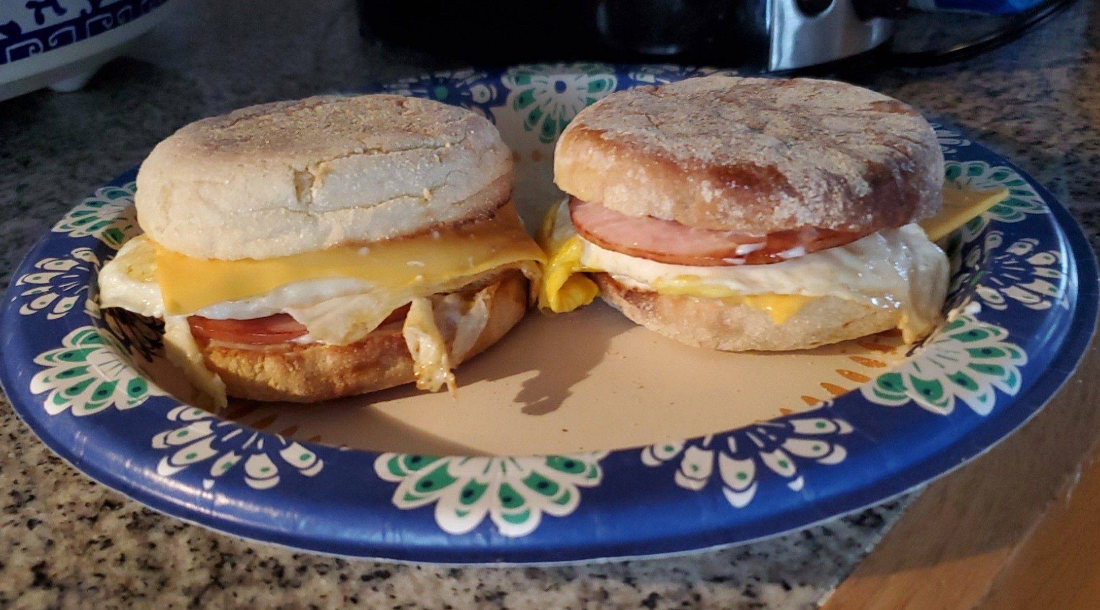 A stack of homemade freezer breakfast sandwiches with fluffy eggs, melty cheese, and crispy bacon on toasted English muffins—perfectly prepped and ready to grab and go.