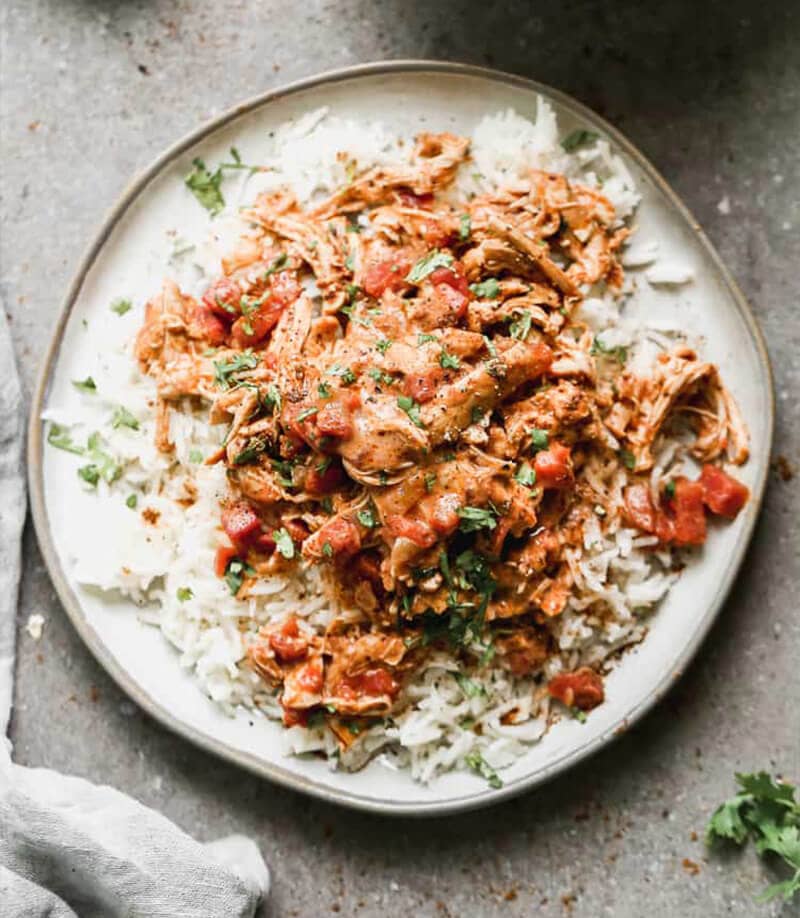 Slow Cooker Tikka Masala served over rice and garnished with herbs. 