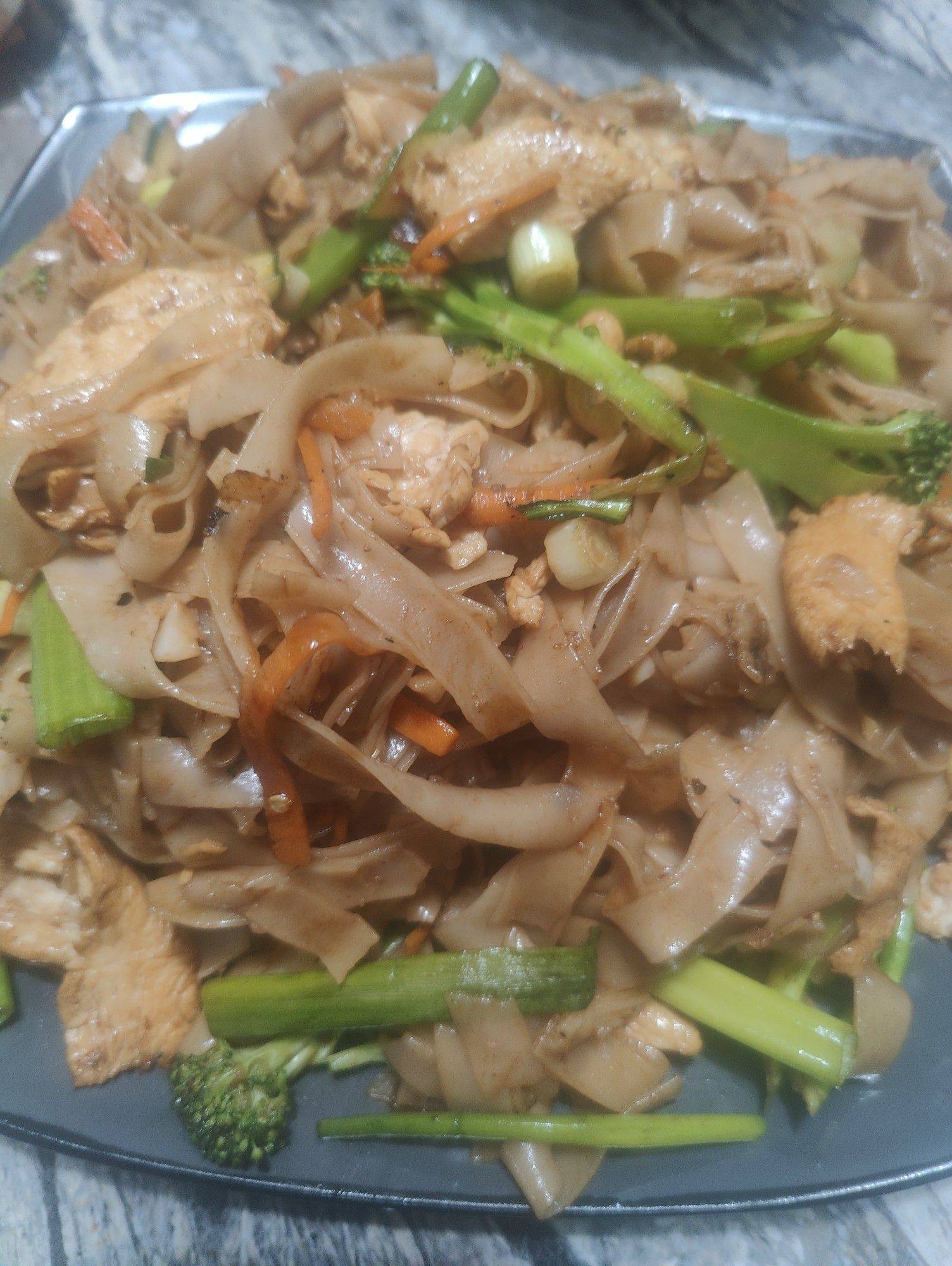 A colorful plate of Thai drunken noodles with wide rice noodles, tender chicken, bell peppers, and fresh basil tossed in a bold, savory sauce. Spicy, saucy, and full of flavor.