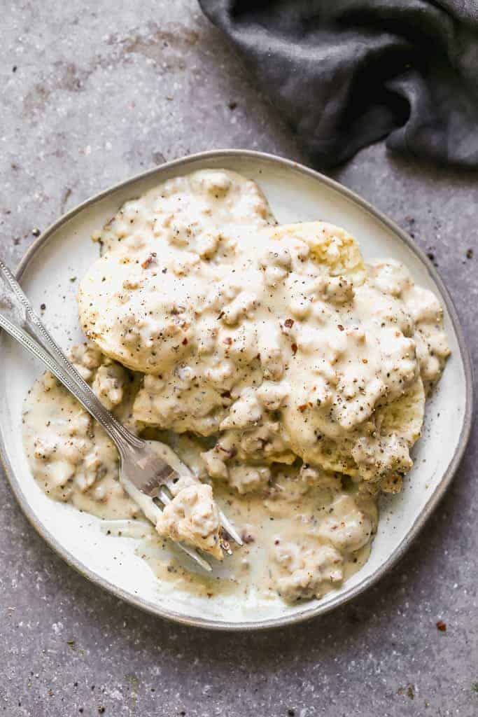 Biscuits and Gravy served on a beige plate with a fork 