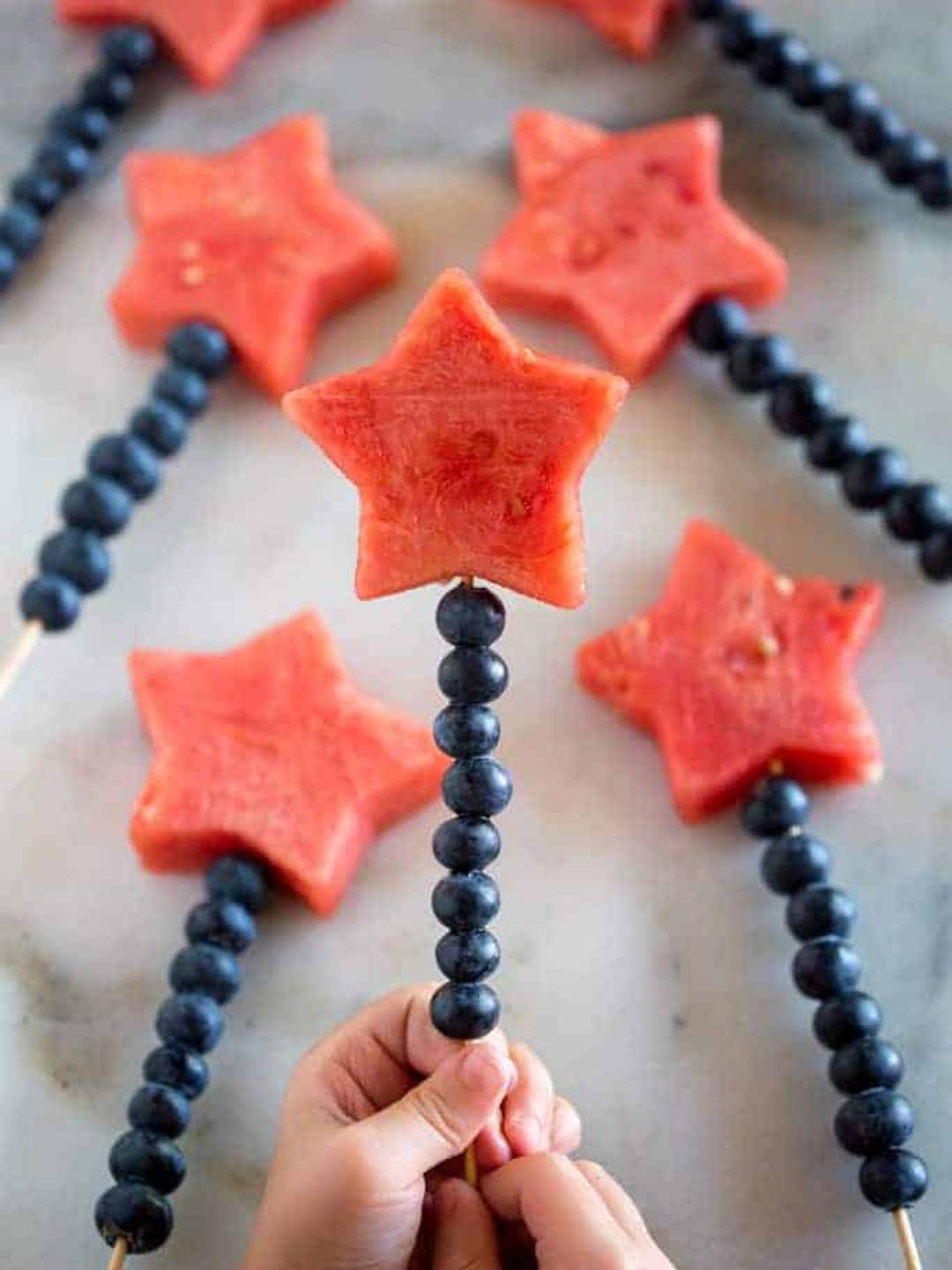 Star shaped watermellon and blueberries on a skewer to resemble sparklers.