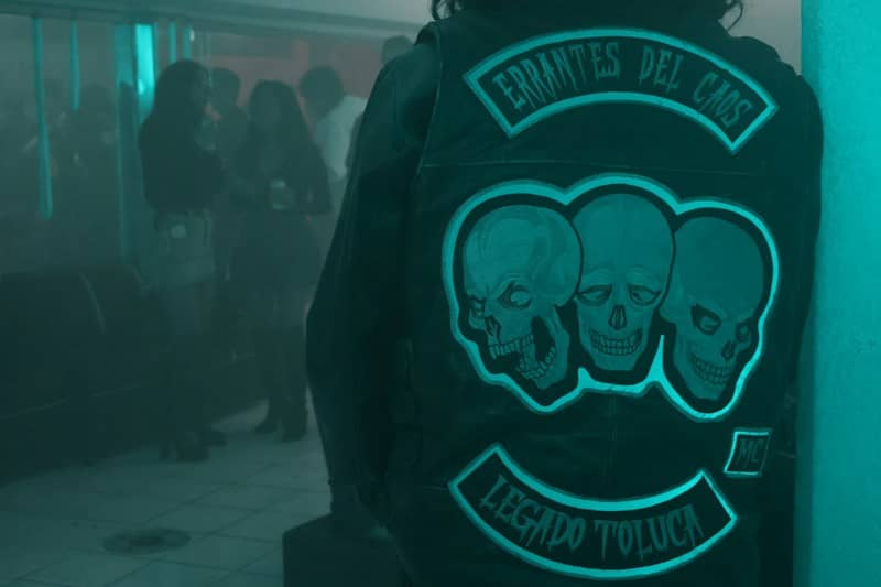 Neon-lit club scene with person wearing a motorcycle club jacket