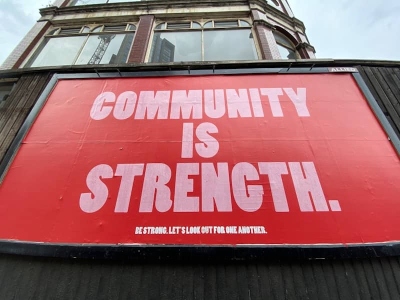 red and white sign that says "Community is Strength"